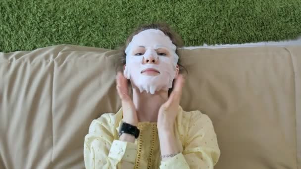 Jeune femme faisant masque facial masque avec masque nettoyant sur le visage dans la cuisine à la maison — Video