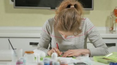 Bir kadın bir ahşap bebek renkli boyalar ile ev stüdyosunda, boyalar Matryoshka boyama