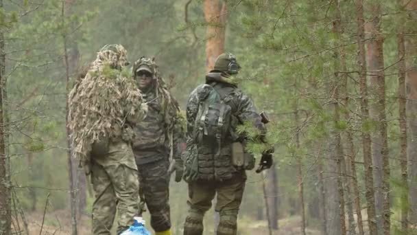 Солдати в камуфляжі з бойовою зброєю виходять за межі лісу з метою захоплення його, військова концепція — стокове відео