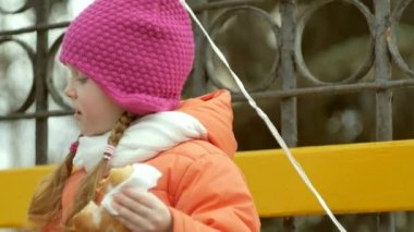 Güzel kız bir bankta oturur ve lezzetli bir tatlı yiyor