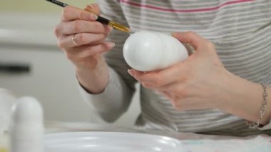 Bir kadın bir ahşap bebek renkli boyalar ile ev stüdyosunda, boyalar Matryoshka boyama, yakın çekim