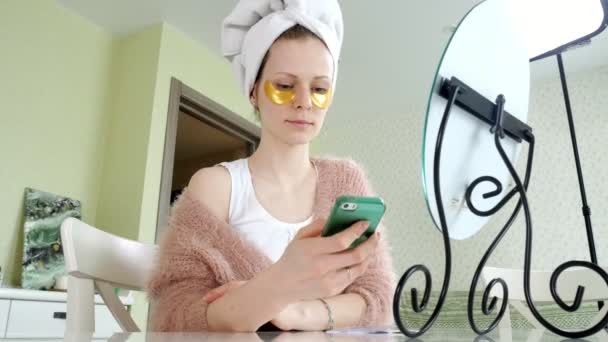 Attractive business woman applying cosmetic facial spots at home, talking on the phone — Stock Video