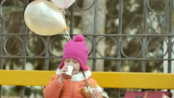 Bella ragazza si siede su una panchina del parco e mangia un delizioso dessert — Video Stock