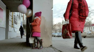 Küçük kız yürüyerek kentin erken baharda bir sokakta renkli balonlar ile
