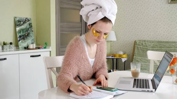 Aantrekkelijke zakenvrouw cosmetische gezichts plekken thuis, toe te passen op die zijn werken achter een laptop — Stockfoto