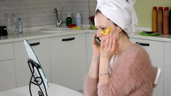 Mujer atractiva espiando parches faciales cosméticos en casa —  Fotos de Stock