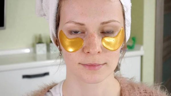 Привлекательная женщина с косметическими нашивками на лице дома — стоковое фото