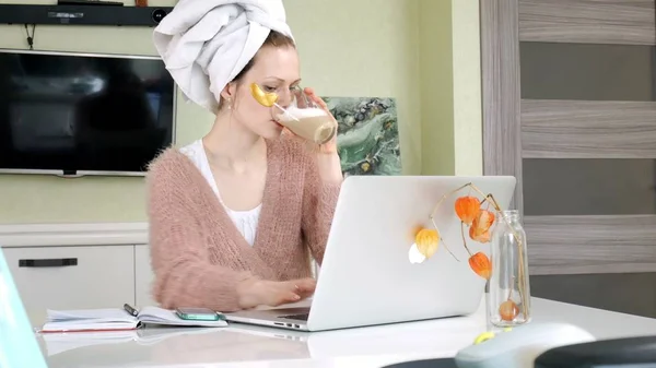 Mulher de negócios atraente aplicando manchas faciais cosméticos em casa, trabalhando atrás do laptop — Fotografia de Stock