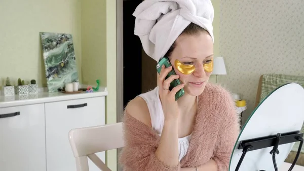 Γυναίκα του ελκυστικού επιχειρηματικού εφαρμογή καλλυντικών προσώπου κηλίδες στο σπίτι, μιλάει στο τηλέφωνο — Φωτογραφία Αρχείου