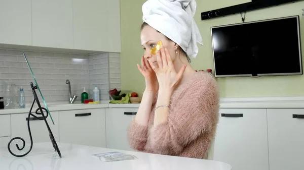 Mujer atractiva espiando parches faciales cosméticos en casa —  Fotos de Stock
