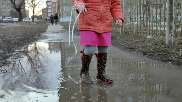 Pequena menina bonita pulando em poças após a chuva — Fotografia de Stock