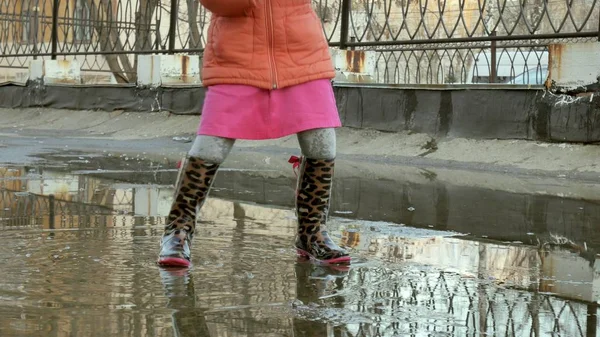 Маленькая красивая девочка прыгает на лужах после дождя — стоковое фото
