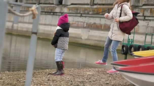 Glad och vacker mor och dotter är mata måsar på stranden vid flodbank — Stockvideo