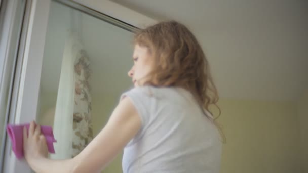 Aantrekkelijk meisje wast windows thuis. Om het huis schoon te maken. — Stockvideo