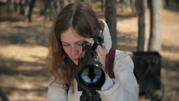 Mulher atraente olha através de um telescópio em uma floresta na margem do rio — Vídeo de Stock