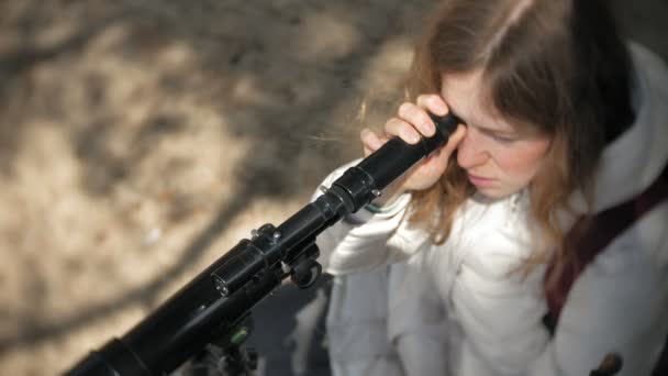 Femme attirante regarde à travers un télescope dans une forêt sur la rive de la rivière — Video