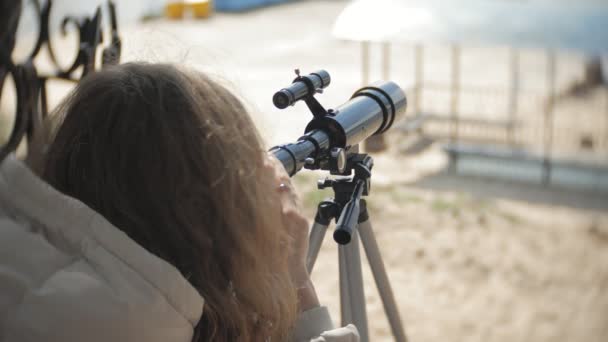 Mujer atractiva mira a través de un telescopio en un bosque en la orilla del río — Vídeo de stock