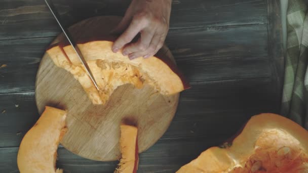 Um homem corta uma abóbora laranja . — Vídeo de Stock