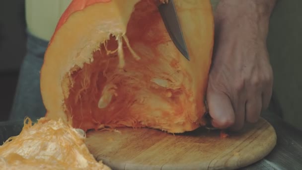 Un uomo taglia una zucca arancione . — Video Stock