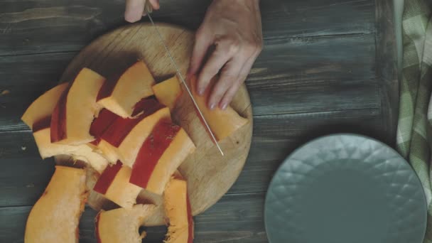 Een man snijdt een oranje pompoen. — Stockvideo