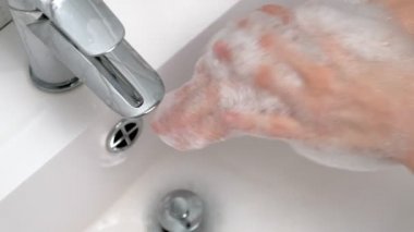 Bir adam ellerini banyoda sabunla yıkıyor. Hijyen