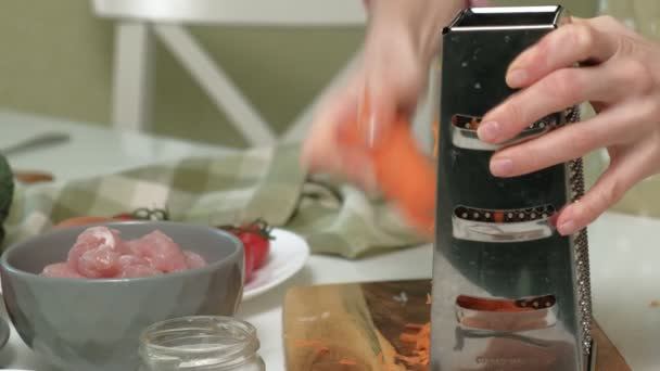 Friss sárgarépát szeletelni egy fémreszelőn az otthoni konyhában.. — Stock videók