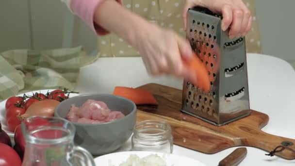 Cortar cenouras frescas em um ralador de metal na cozinha doméstica . — Vídeo de Stock