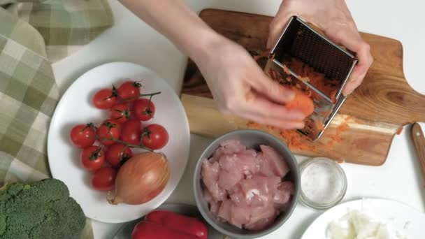 Slicing fresh carrots on a metal grater in the home kitchen. — Stock Video