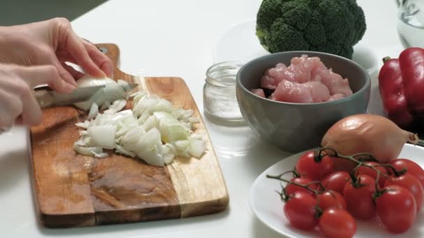 Cortar cebolas frescas em uma tábua de madeira na cozinha doméstica — Vídeo de Stock