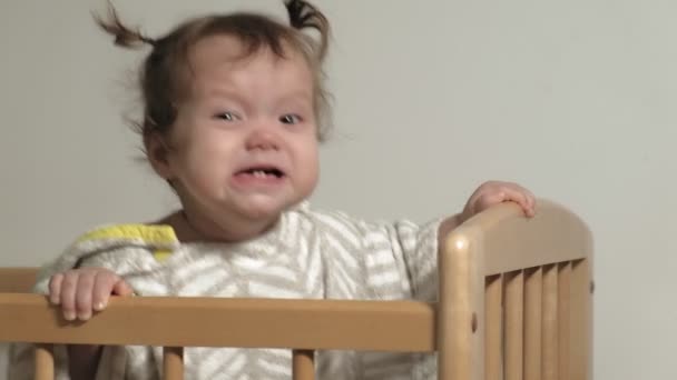 Uma criança pequena brinca no berço . — Vídeo de Stock