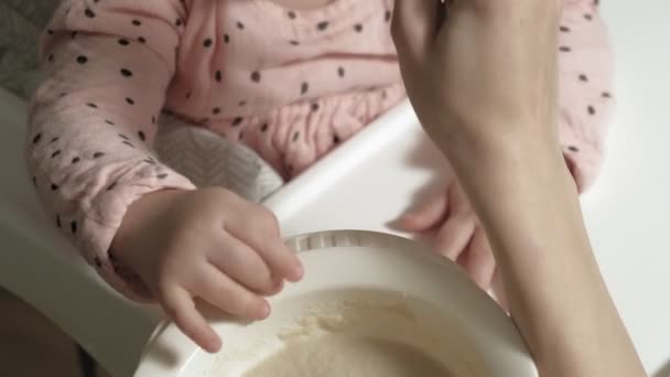 Mamá alimenta a una niña en una silla alta . — Vídeos de Stock