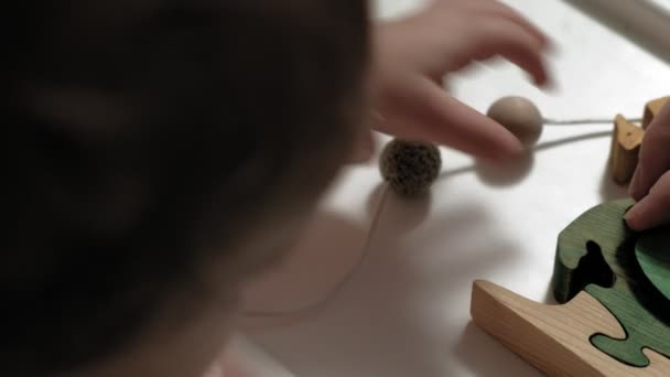 La bambina sta giocando con un giocattolo di legno. Lo sviluppo delle capacità motorie — Video Stock