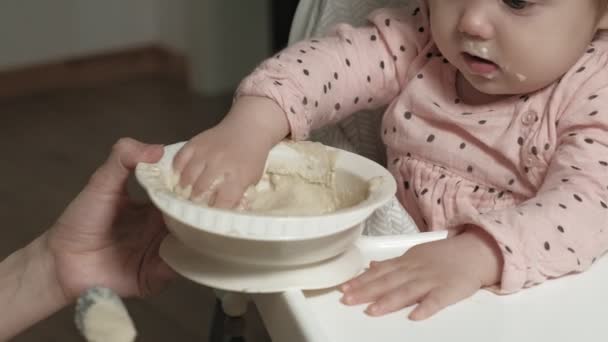 Anya etet egy kislányt egy etetőszékben.. — Stock videók