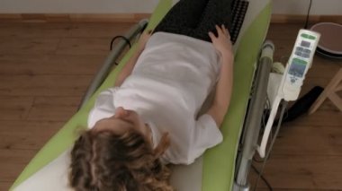Bir kadın masaj elektronik yatağında yatıyor..