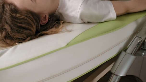 Een vrouw ligt op een massage elektronisch bed. — Stockvideo