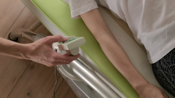 Une femme se couche sur un lit électronique de massage . — Video