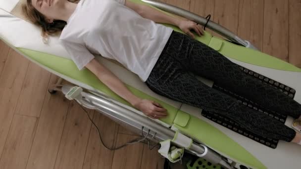 Una donna si trova su un letto elettronico massaggio . — Video Stock