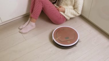 Genç bir kadın robotu süpürüyor..