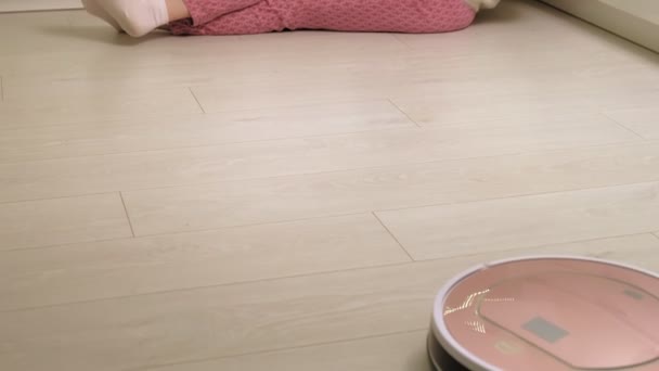 Een jonge vrouw stofzuigt een robot. — Stockvideo