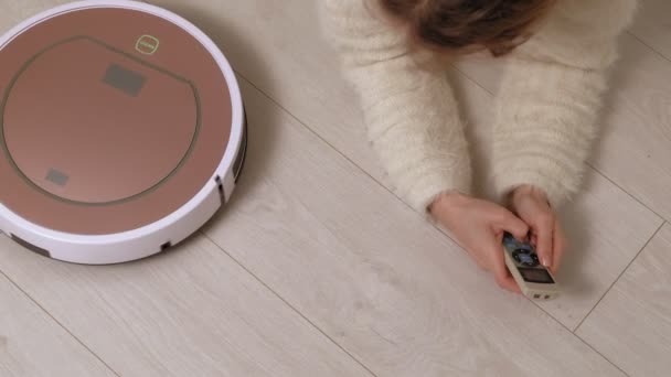 A young woman controls a robot with a vacuum cleaner. — Stock Video