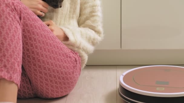 A young woman is vacuuming a robot. — Stock Video