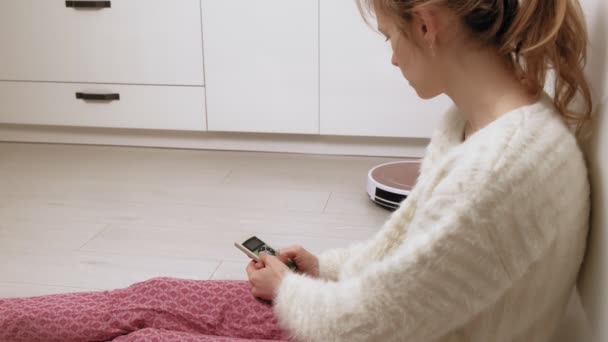 A young woman controls a robot with a vacuum cleaner. — Stock Video