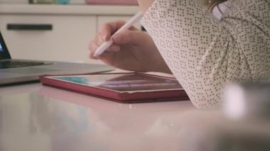 Genç bir kadın evdeki bilgisayar tabletinde çalışıyor..