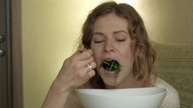 Genç kadın yeşil salata yiyor..