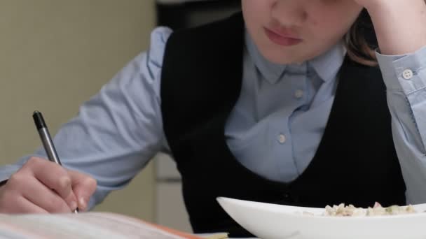 Adolescente en un uniforme escolar hace la tarea — Vídeo de stock