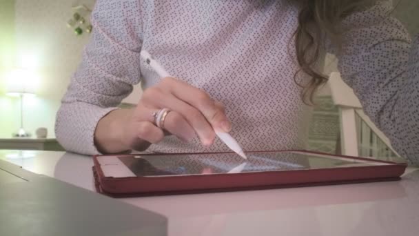 Una mujer joven trabaja en una tableta de computadora en casa . — Vídeo de stock