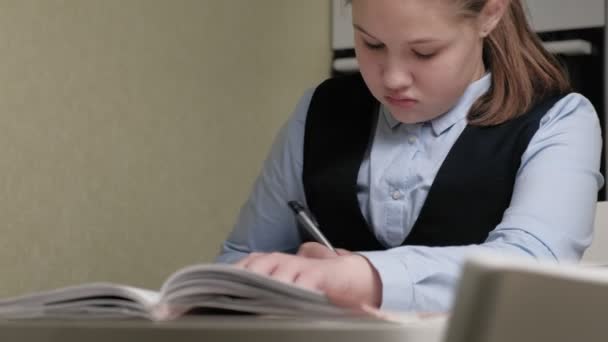 Adolescente en un uniforme escolar hace la tarea — Vídeos de Stock