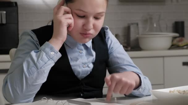 A tinédzser lány iskolai egyenruhában házi feladatot csinál. — Stock videók