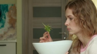 Genç kadın yeşil salata yiyor..