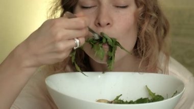 Genç kadın yeşil salata yiyor..